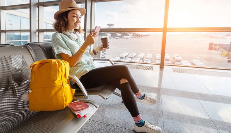Junge Frau sitzt in der Abflughalle.