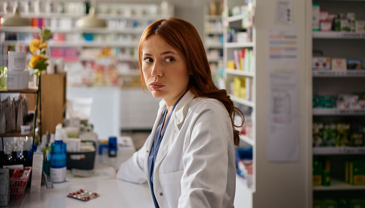 Apothekerin steht enttäuscht in der Apotheke.