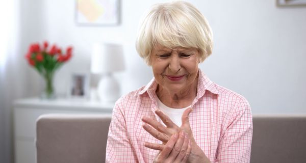 Ältere Frau hält sich die Hand.