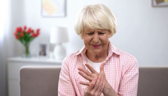 Ältere Frau hält sich die Hand.