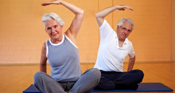 Frau und Mann 60+ machen Gymnastik.