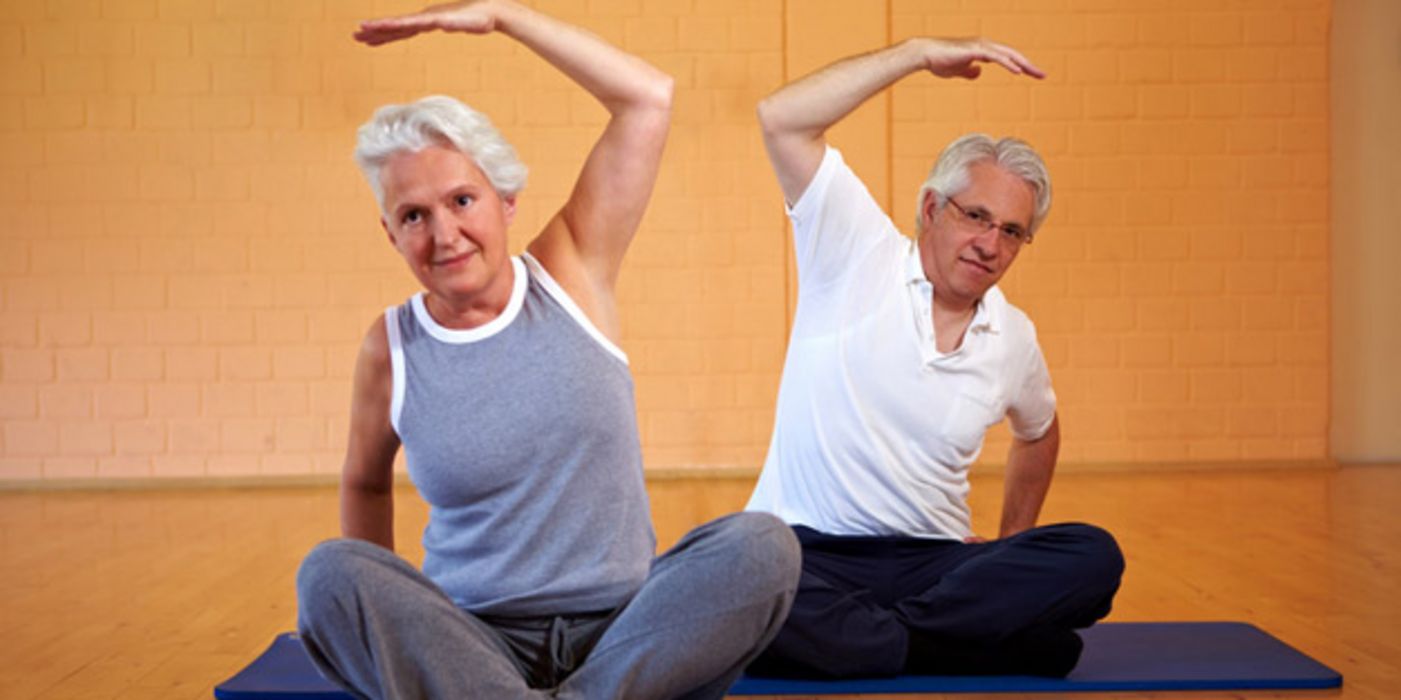 Frau und Mann 60+ machen Gymnastik.