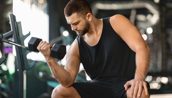 Ein Mann sitzt in einem Fitnessstudio und trainiert seinen Arm.