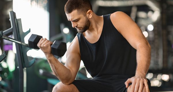Ein Mann sitzt in einem Fitnessstudio und trainiert seinen Arm.