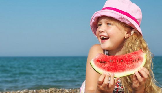 Mädchen am Strand isst Melone.