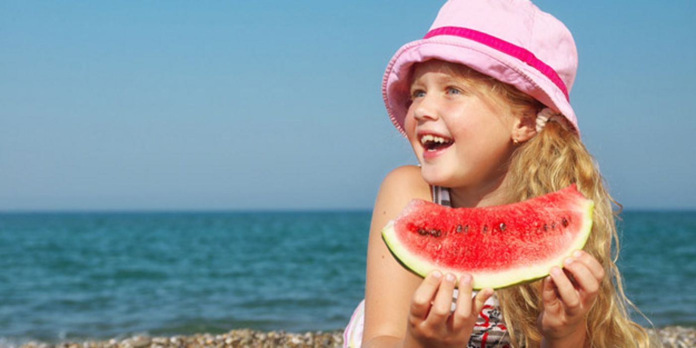 Mädchen am Strand isst Melone.