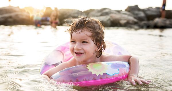 Kind mit Schwimmring im Wasser.