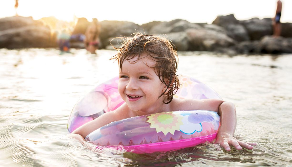 Kind mit Schwimmring im Wasser.