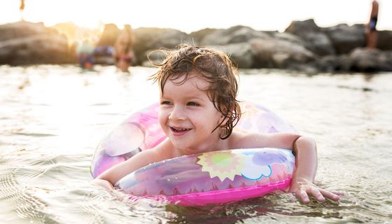 Kind mit Schwimmring im Wasser.