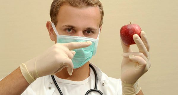 Arzt hält einen Apfel in der Hand.