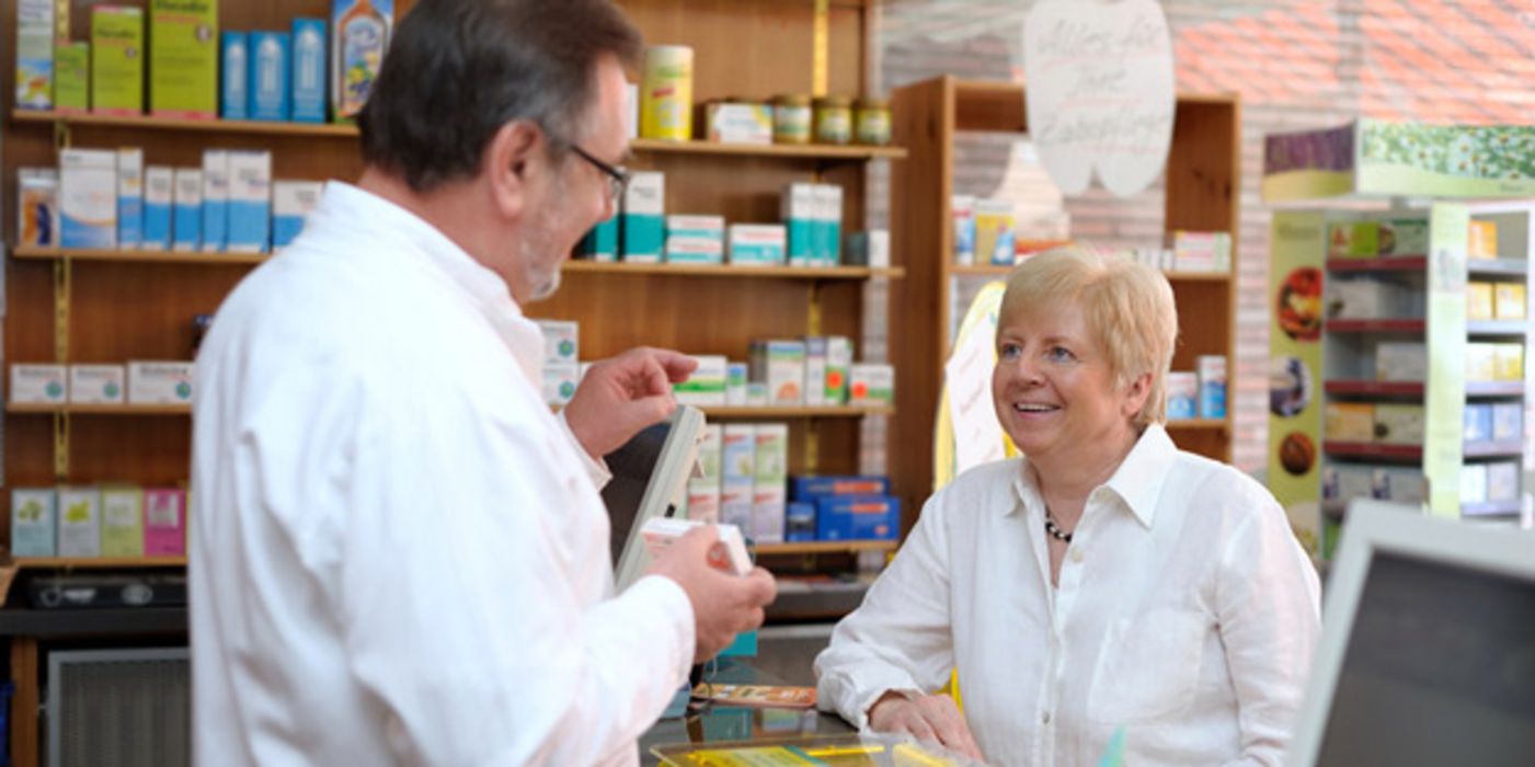 Apotheker berät Seniorin zu einem Arzneimittel