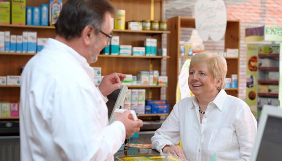 Apotheker berät Seniorin zu einem Arzneimittel