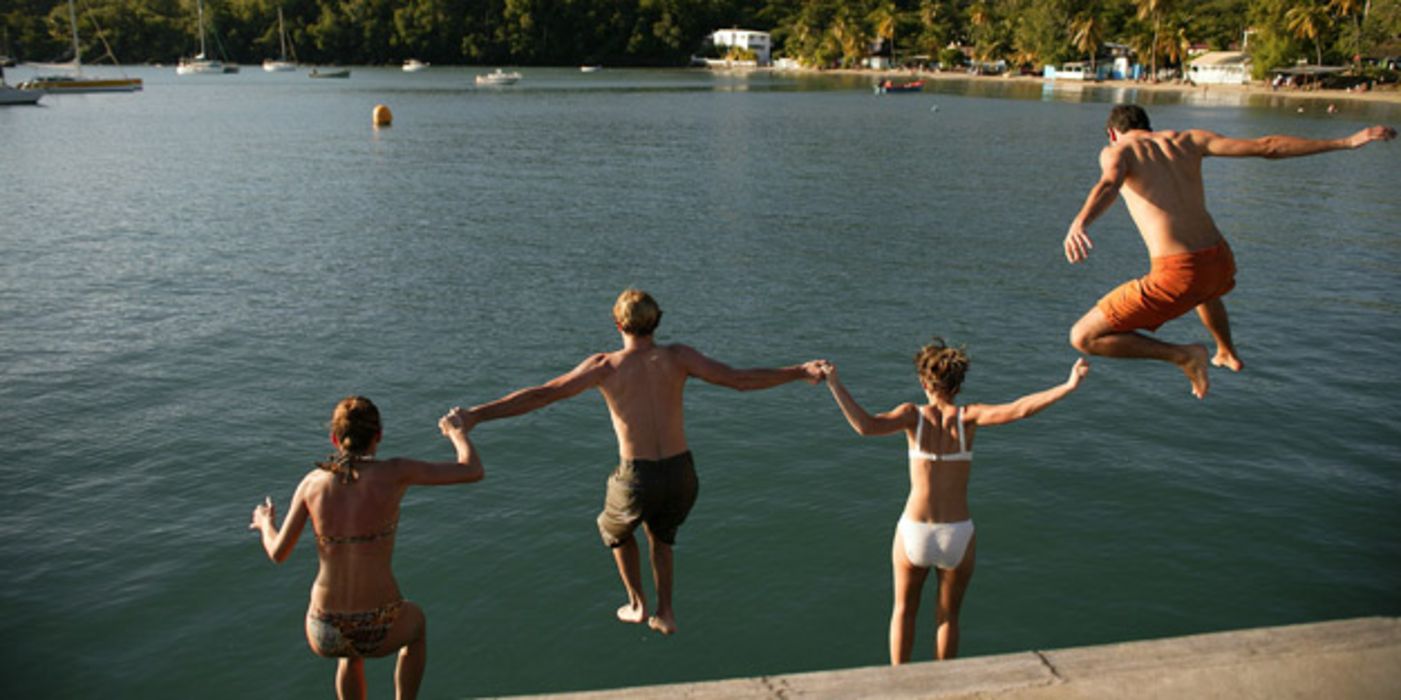 Vier junge Leute springen in einen See.