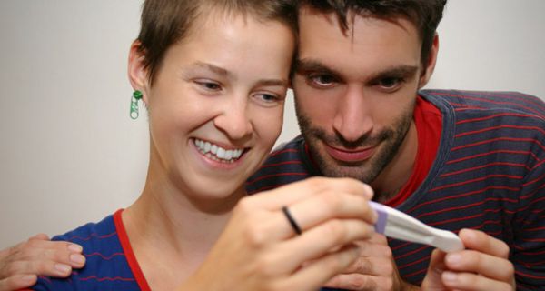 Junges Paar betrachtet erfreut einen Schwangerschaftstest