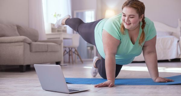 Frau macht Gymnastik vor dem PC.