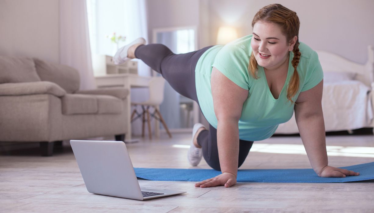 Frau macht Gymnastik vor dem PC.