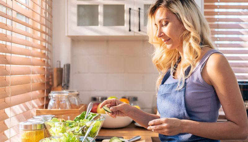 Junge Frau bereitet mäßig begeistert einen Salat zu.