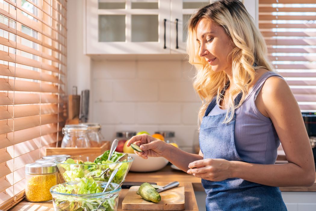 Junge Frau bereitet mäßig begeistert einen Salat zu.