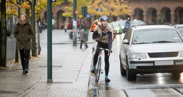 Auto und Fahrradfahrer warten an einer roten Ampel