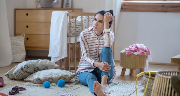 Junge Frau, sitzt verzweifelt im Kinderzimmer.