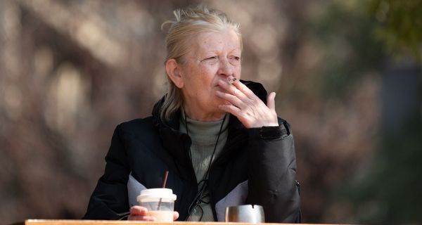 Ältere Frau raucht draußen.