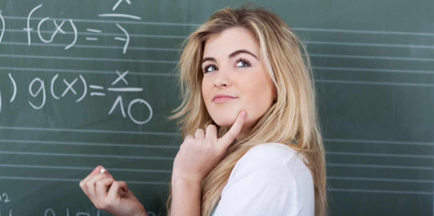 Schülerin vor einer Tafel grübelt angesichts einer schweren Mathe-Aufgabe