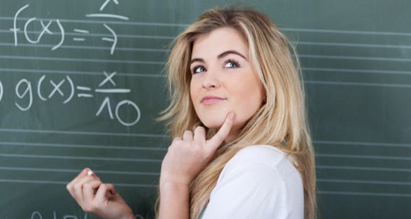 Schülerin vor einer Tafel grübelt angesichts einer schweren Mathe-Aufgabe