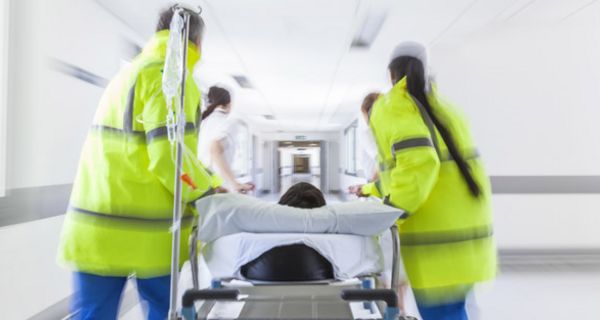 Einlieferung eines Notfalls ins Krankenhaus, Liege und Notfallpersonal, von hinten fotografiert, rechts und links neben Liege, Oberkopf von Patient zu sehen