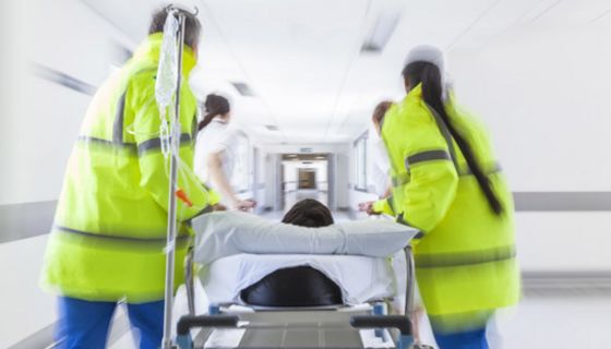 Einlieferung eines Notfalls ins Krankenhaus, Liege und Notfallpersonal, von hinten fotografiert, rechts und links neben Liege, Oberkopf von Patient zu sehen