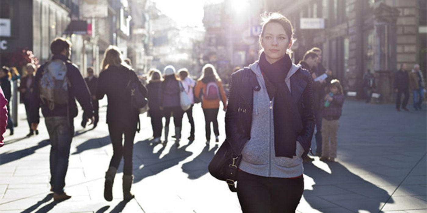 Fußgängerzone im Gegenlicht/Zwielicht, im Vordergrund junge Frau
