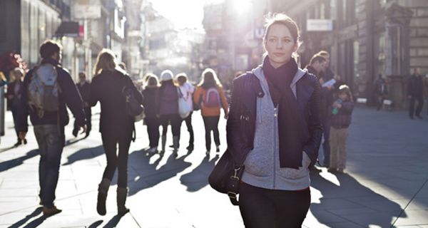 Fußgängerzone im Gegenlicht/Zwielicht, im Vordergrund junge Frau