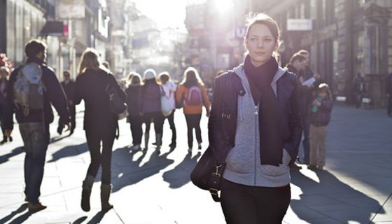 Fußgängerzone im Gegenlicht/Zwielicht, im Vordergrund junge Frau