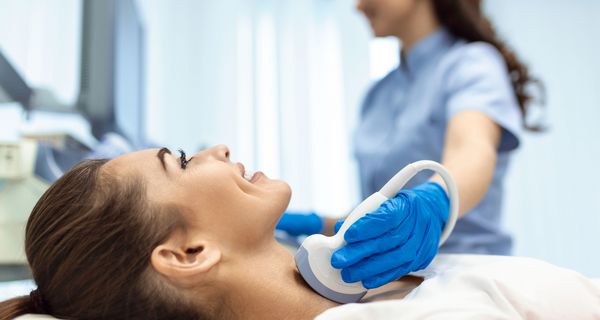 Frau, erhält einen Ultraschall ihrer Schilddrüse