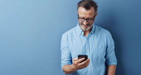 Mann, hält ein Smartphone in der Hand.