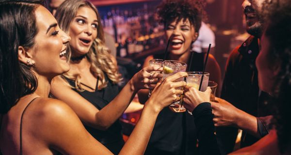 Vier junge Frauen und ein Mann stoßen mit Cocktails an. 