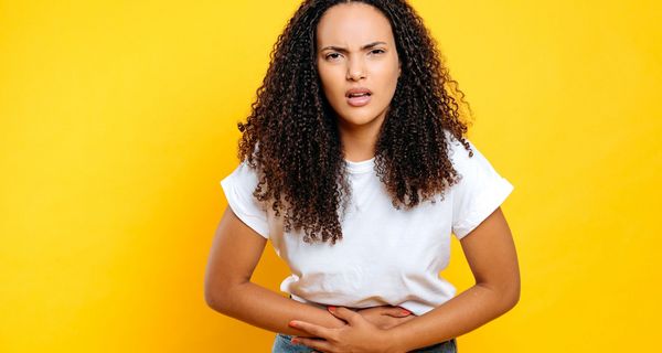 Junge Frau hält sich den Bauch und schaut genervt.