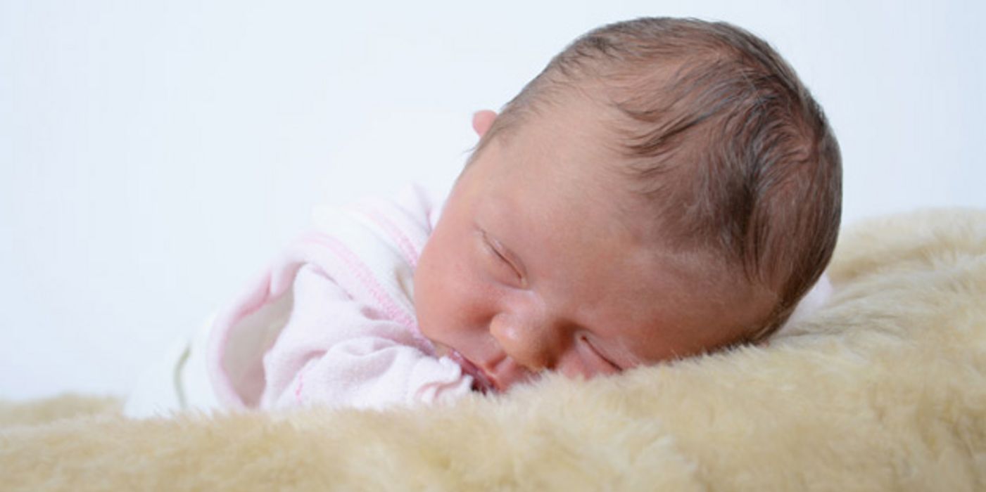 Nahaufnahme: schlafender Säugling, mit einer Wange auf Schaffell