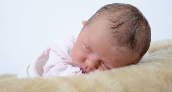 Nahaufnahme: schlafender Säugling, mit einer Wange auf Schaffell
