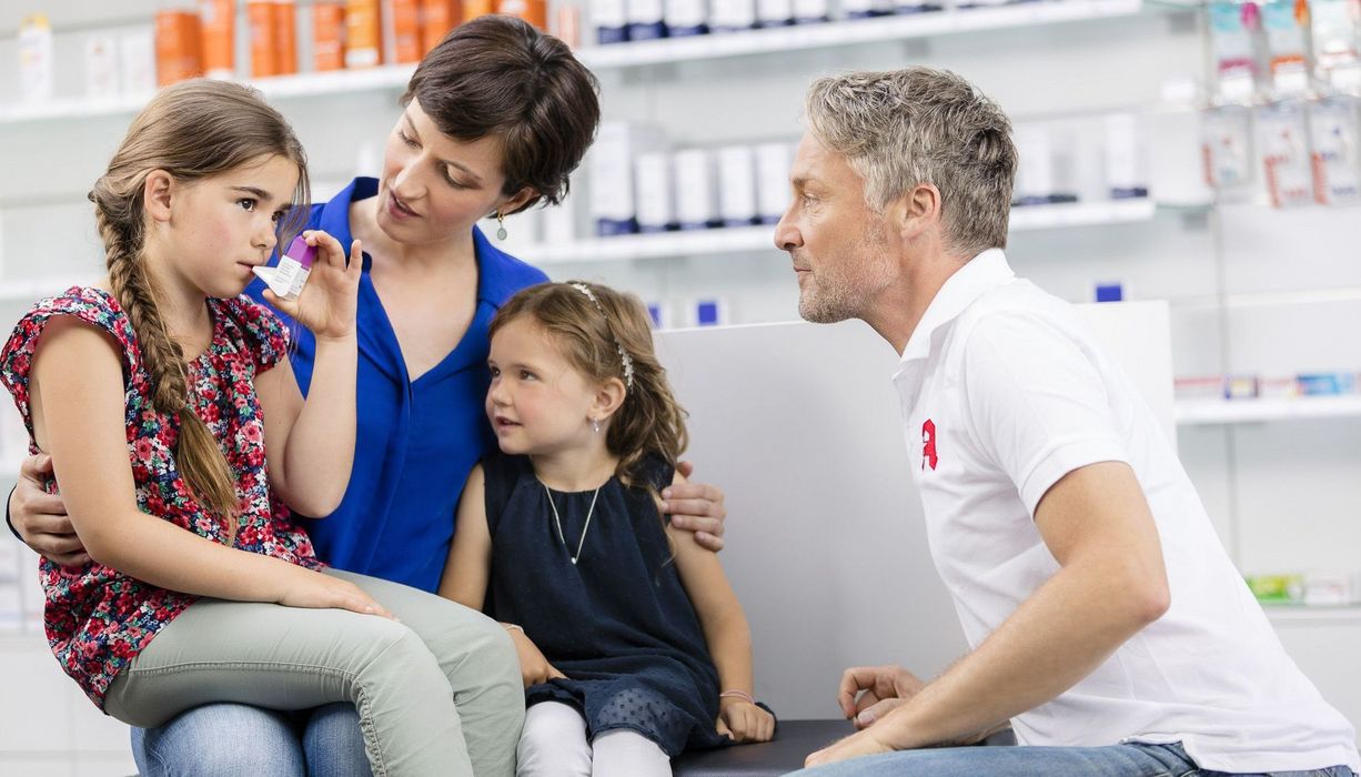 Apotheker berät Familie bei der Anwendung eines Asthmasprays.