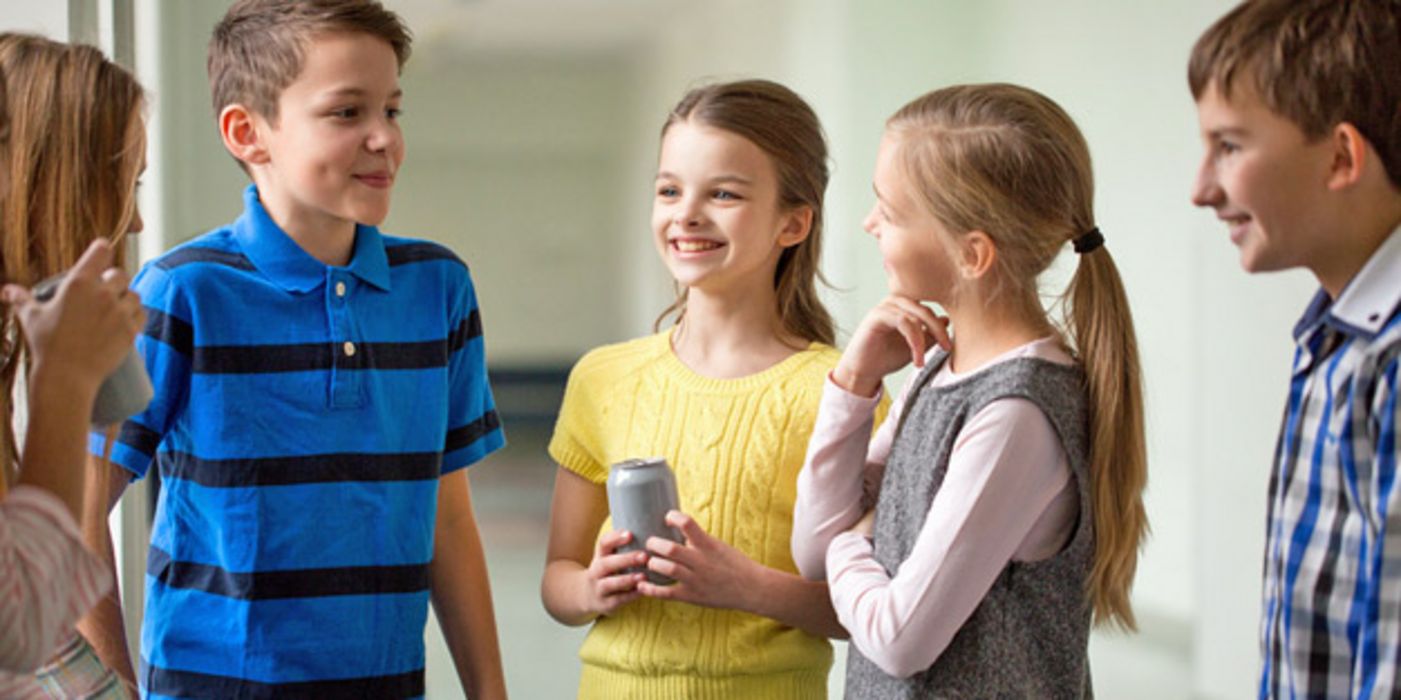 Gruppe von SchülerInnen, ca. 11-jährig, unterhalten sich, ein Mädchen hält eine Dose (Energydrink) in der Hand.