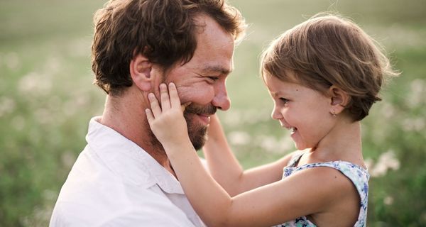 Vater mit Tochter, die sein Gesicht streichelt.