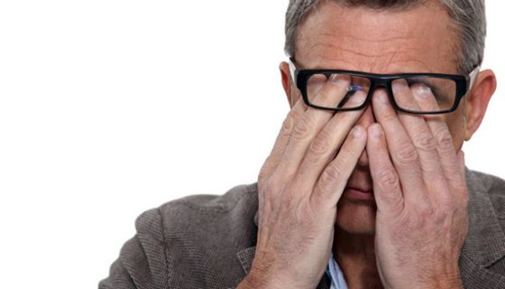 Mann, ca. 50 Jahre alt, reibt sich unter seiner Brille die Augen.