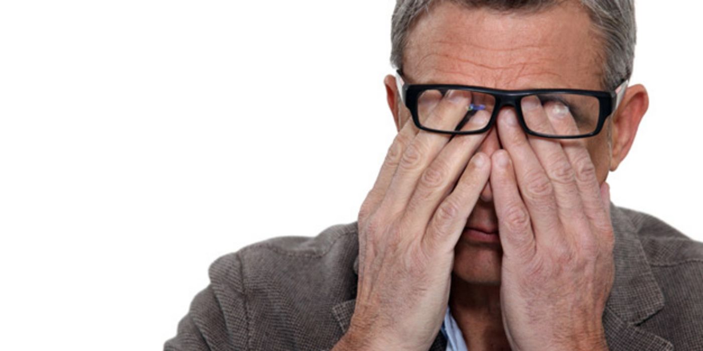 Mann, ca. 50 Jahre alt, reibt sich unter seiner Brille die Augen.