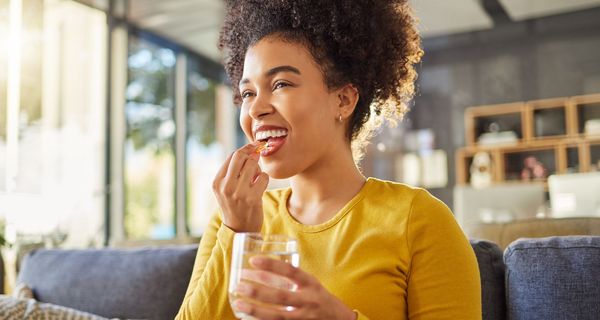 Junge Frau nimmt eine Kapsel ein.