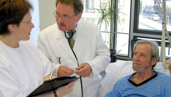 Arzt und Ärztin besprechen sich am Bett eines Patienten
