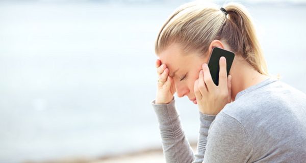 Junge Frau im Profil telefoniert mit besorgter Miene