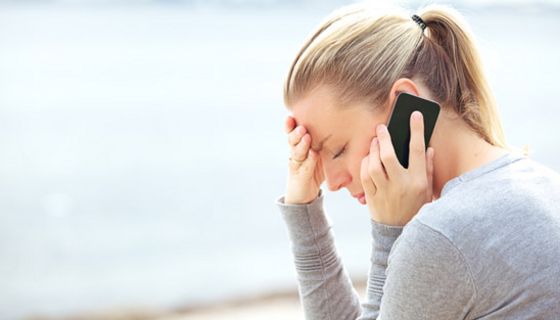Junge Frau im Profil telefoniert mit besorgter Miene