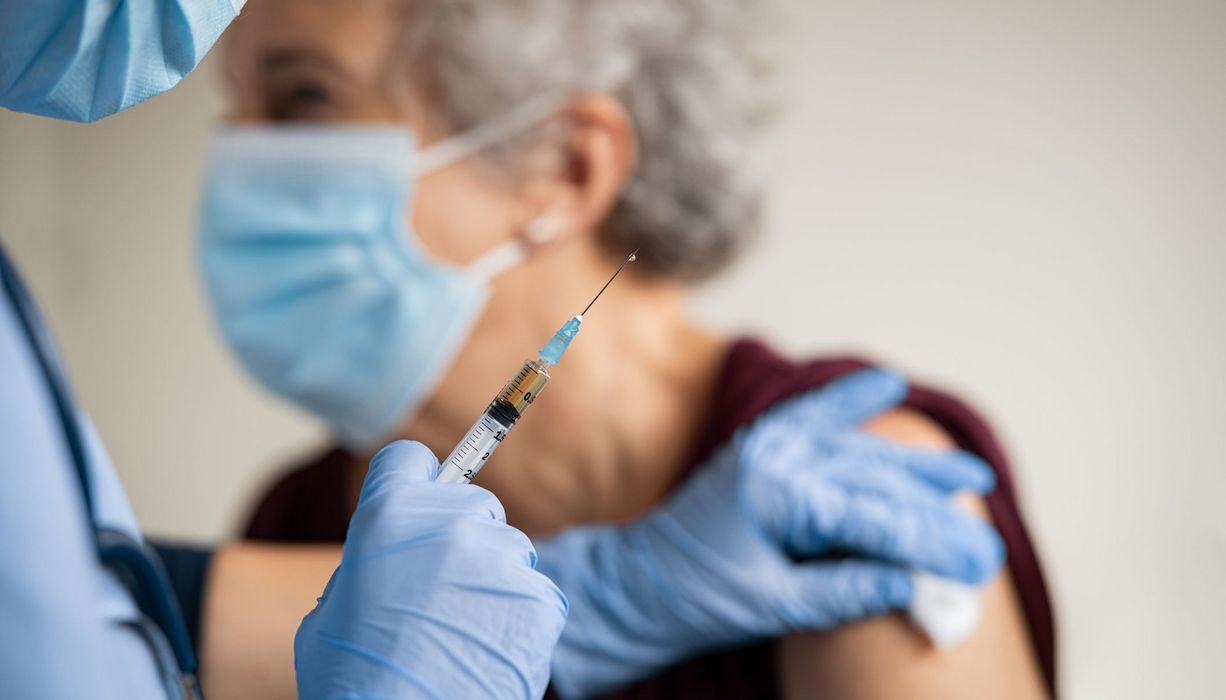 Ältere Frau mit Maske, erhält eine Impfung.