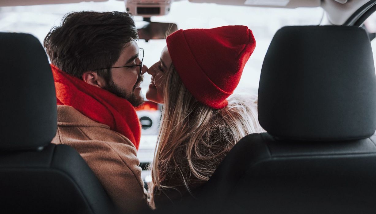 Mann und Frau, sitzen im Auto und küssen sich.