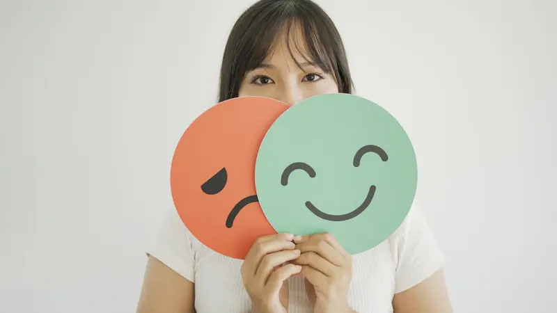 Frau hält Schilder mit lachendem und weinendem Gesicht.